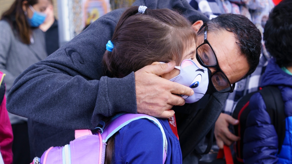 A father kisses his daughter prior to entering the school yard at the Philippe-Labarre Elementary School in Montreal, on Thursday, August 27, 2020. Thousands of Quebec students return to class in the shadow of the COVID-19 pandemic. THE CANADIAN PRESS/Paul Chiasson