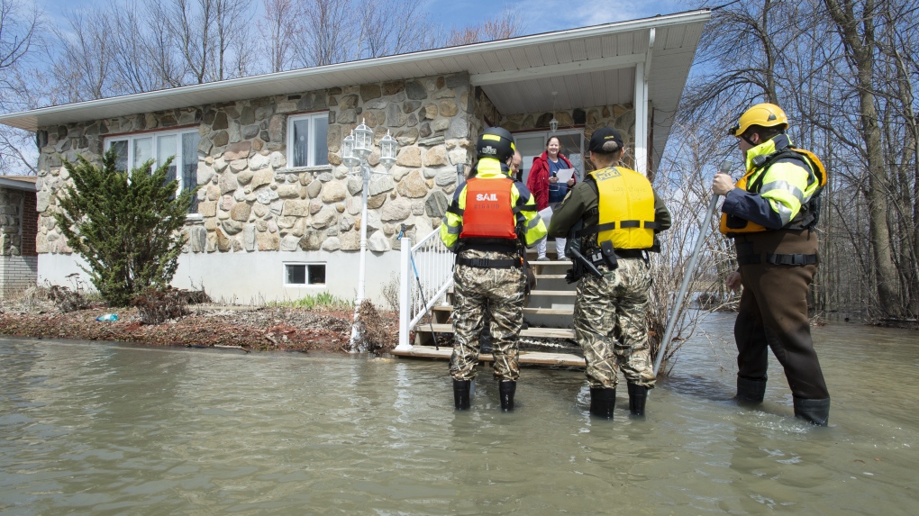 Quebec Provincial police and local firemen check up on a resident in a flooded neighbourhood in Rigaud, Que. on Tuesday, April 23, 2019. THE CANADIAN PRESS/Paul Chiasson