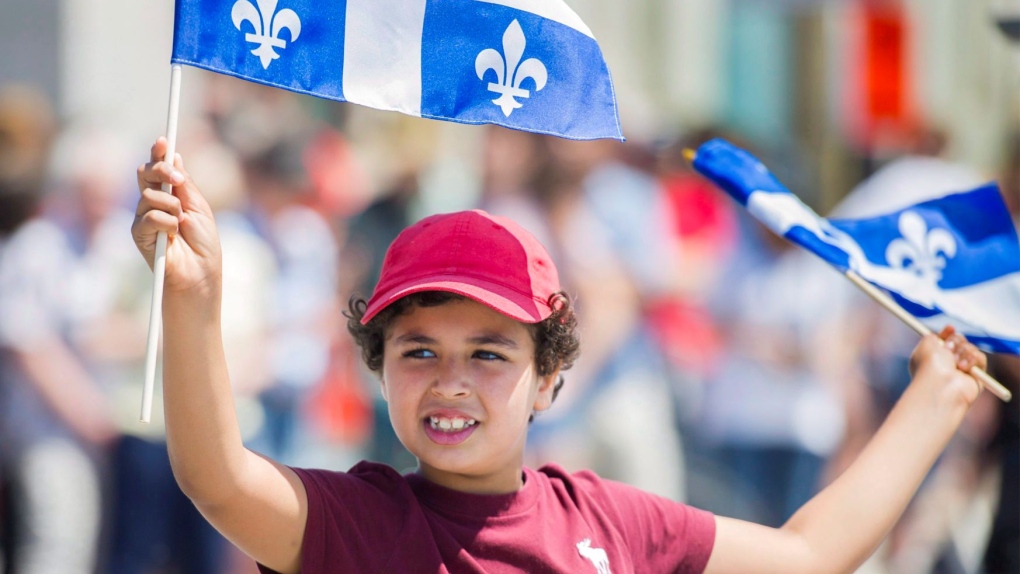 A young boy smiles as he waves Quebec flags during the annual Saint-Jean-Baptiste day parade in Montreal, Saturday, June 24, 2017. THE CANADIAN PRESS/Graham Hughes