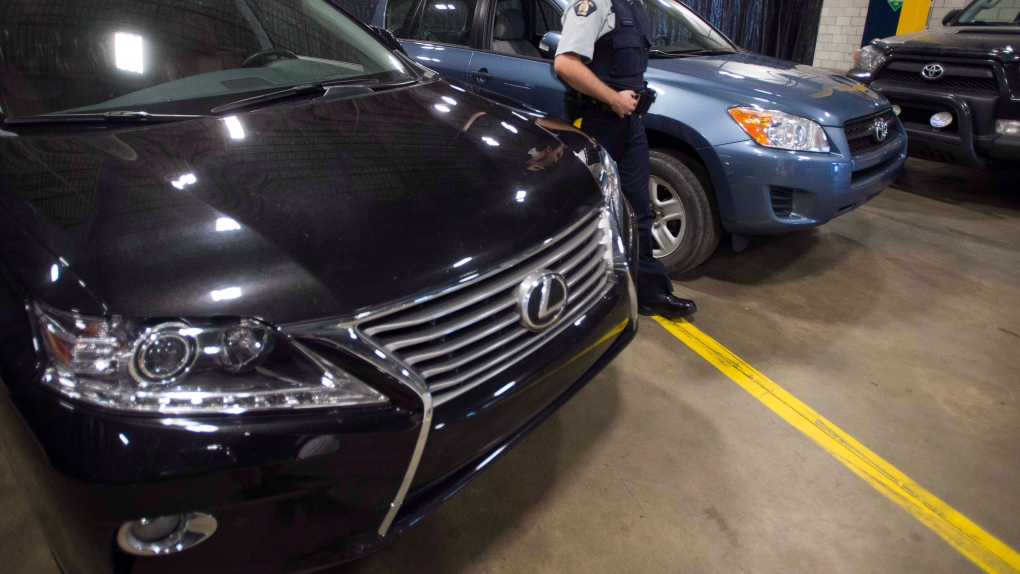FILE PHOTO - An RCMP investigator walks past some of the luxury vehicles that were seized from a containers at a news conference Thursday, July 17, 2014 in Montreal.THE CANADIAN PRESS/Ryan Remiorz
