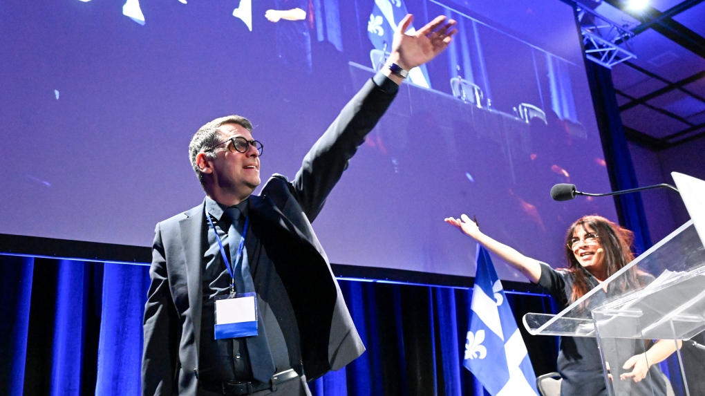 Quebec Conservative Leader Eric Duhaime, left, waves to delegates at the end of his opening speech of the party’s congress, Saturday, November 18, 2023 in Levis, Que. Former party candidate Anne Casabonne, right, raises her hand. THE CANADIAN PRESS/Jacques Boissinot