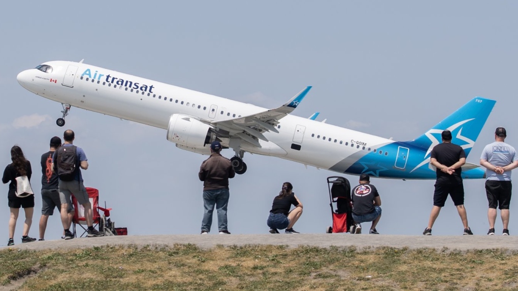 People look on as an Air Transat plane takes off at Trudeau in Montreal, Sunday, June 11, 2023. THE CANADIAN PRESS/Graham Hughes