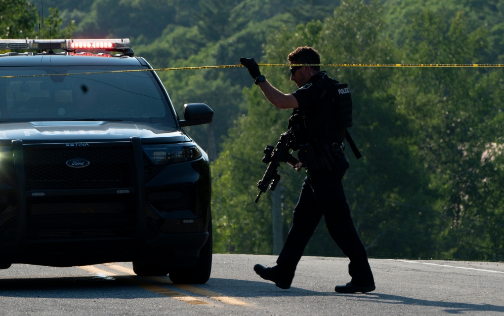 A police officer crosses police tape near Mont Cascades water park in Cantley, Que. on Wednesday, July 14, 2021. A police operation is underway at Mont Cascades, a water park in western Quebec, after someone allegedly pointed what appeared to be a gun at an employee. THE CANADIAN PRESS/Adrian Wyld