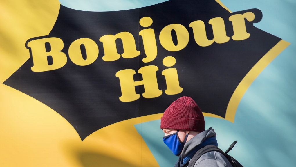 A man wears a face mask as he walks by a sign reading 'Bonjour, Hi' in Montreal, Sunday, October 25, 2020, as the COVID-19 pandemic continues in Canada and around the world. THE CANADIAN PRESS/Graham Hughes