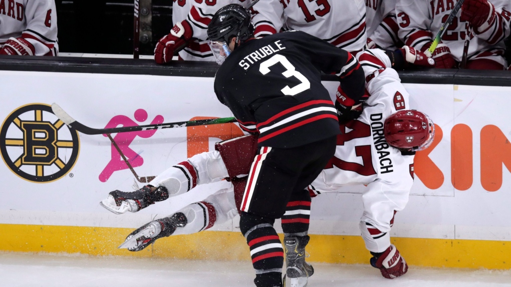 Harvard forward Casey Dornbach (47) is checked against the boards by Northeastern defenseman Jayden Struble (3) during the second period of the NCAA hockey Beanpot Tournament in Boston, Monday, Feb. 3, 2020. (AP Photo/Charles Krupa)