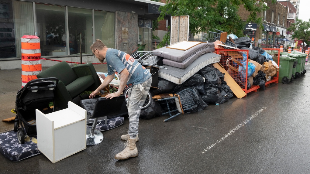 A man looks for salvageable pieces among discarded household items left on the sidewalk after last weekend’s moving day, in Montreal, Tuesday, July 4, 2023. THE CANADIAN PRESS/Ryan Remiorz