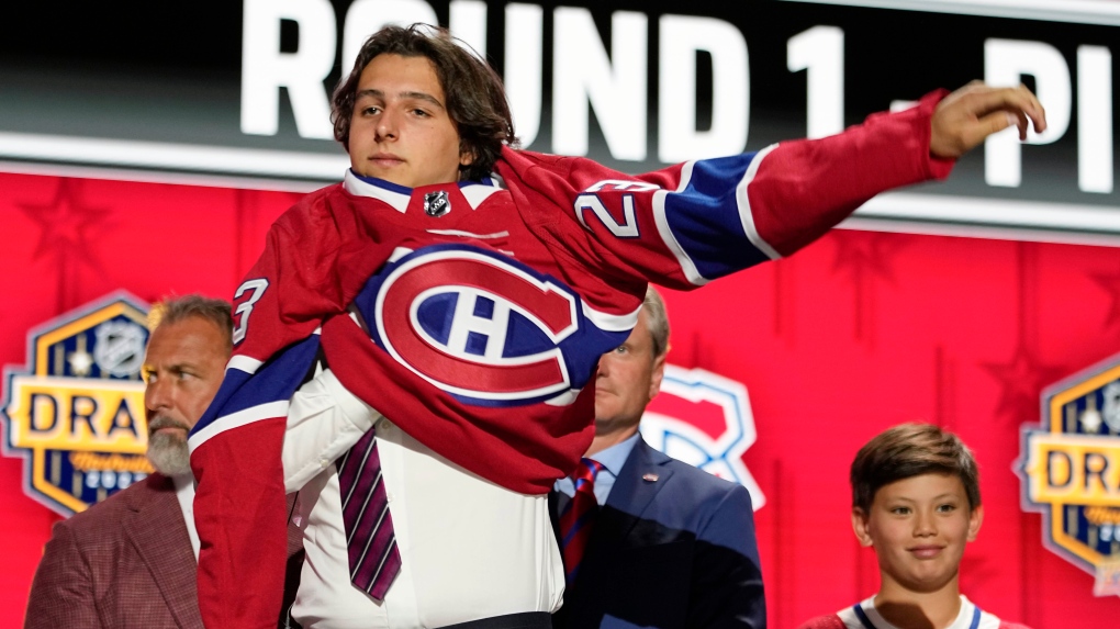David Reinbacher puts on a Montreal Canadiens jersey after being picked by the team during the first round of the NHL hockey draft Wednesday, June 28, 2023, in Nashville, Tenn. The Canadiens signed fifth-overall draft pick Reinbacher to a three-year, entry-level contract on Wednesday. THE CANADIAN PRESS/AP/George Walker IV