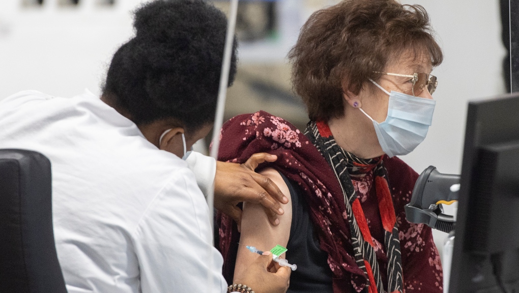 A woman receives a COVID-19 booster vaccine dose at the Olympic Stadium in Montreal, Monday, Dec. 27, 2021. (Graham Hughes, The Canadian Press)