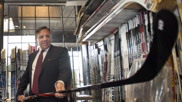 Coalition Avenir Quebec leader Francois Legault checks out a hockey stick during a visit to a sports